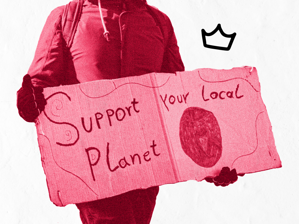 A person holding a cardboard sign saying “Support your local planet”